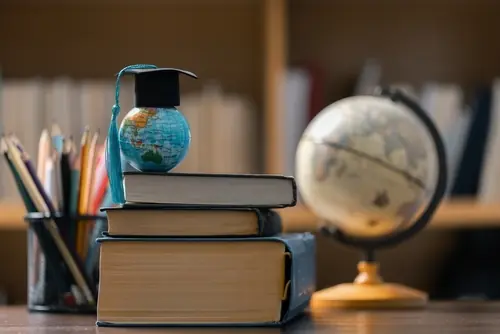 How to Get a Scholarship to Study Abroad 2 Image of a stack of books with globes on a table.