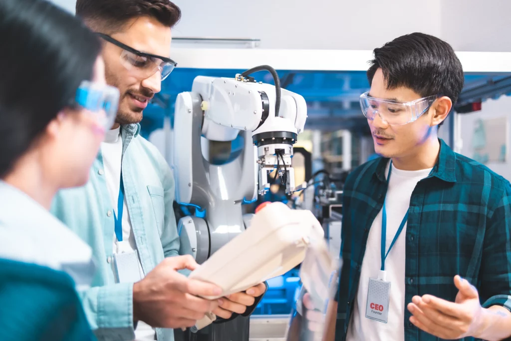 College engineering students reviewing a lab assignment beside a robot.
